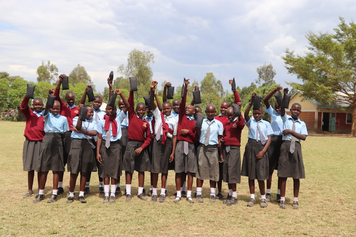 School girls in Kenya holding up reusable sanitary pads